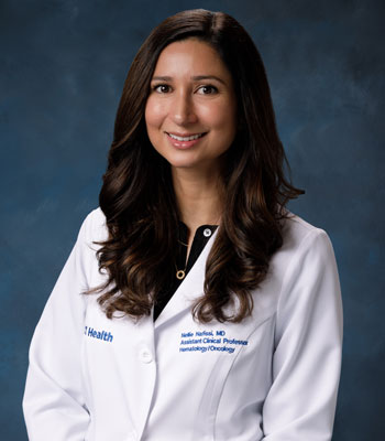 uci health breast cancer specialist dr. nellie nafissi wearing a white coat in front of a blue studio background