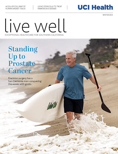 Prostate cancer survivor Steve Mellem heads into the waves with his paddleboard on the cover of the winter 2023 issue of Live Well magazine. 