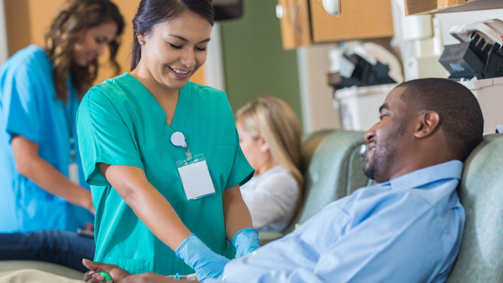man donating blood while attended to by a phlebotomist
