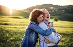 2021 Parkinson's Disease Symposium woman hugging man with sun glow green grass backround