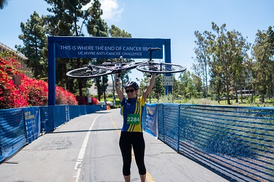 woman poses with bike at Anti-Cancer Challenge finish line