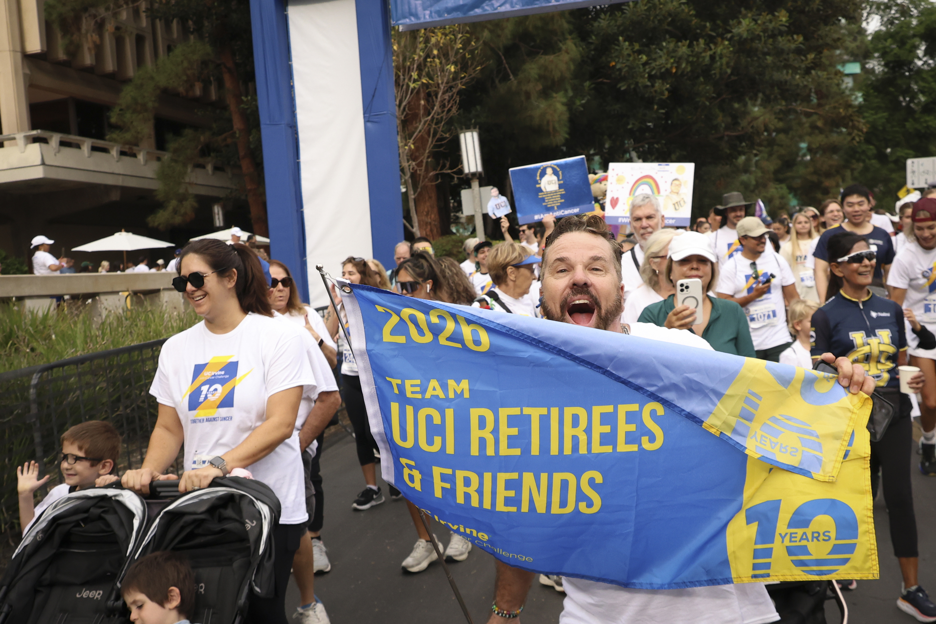 an anti-cancer challenge participant holds a banner celebrating uci retirees and their team during the event