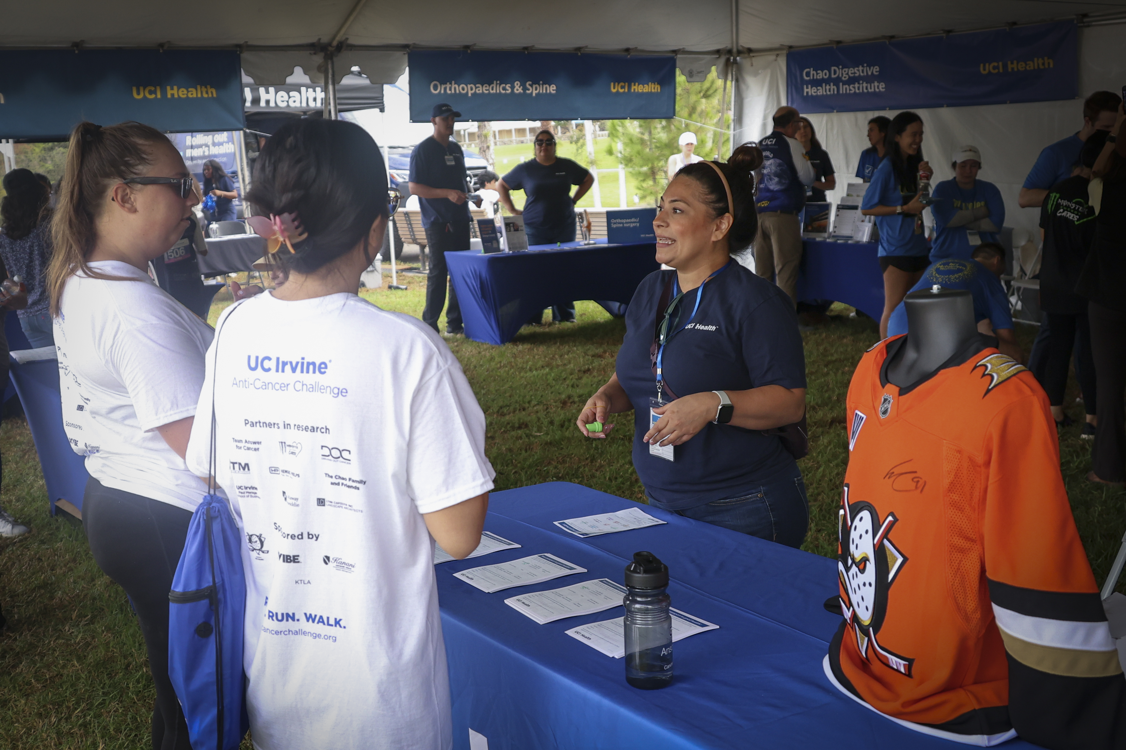 co-workers speak to uc irvine anti-cancer challenge attendees at a booth during  the 2026 uc irvine anti-cancer challenge 