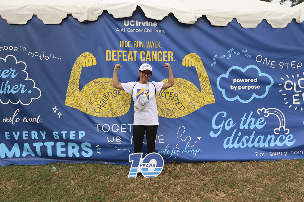 an anti cancer challenge at uc Irvine participant poses in front of a wall with encouraging phrases like go the distance and every step matters