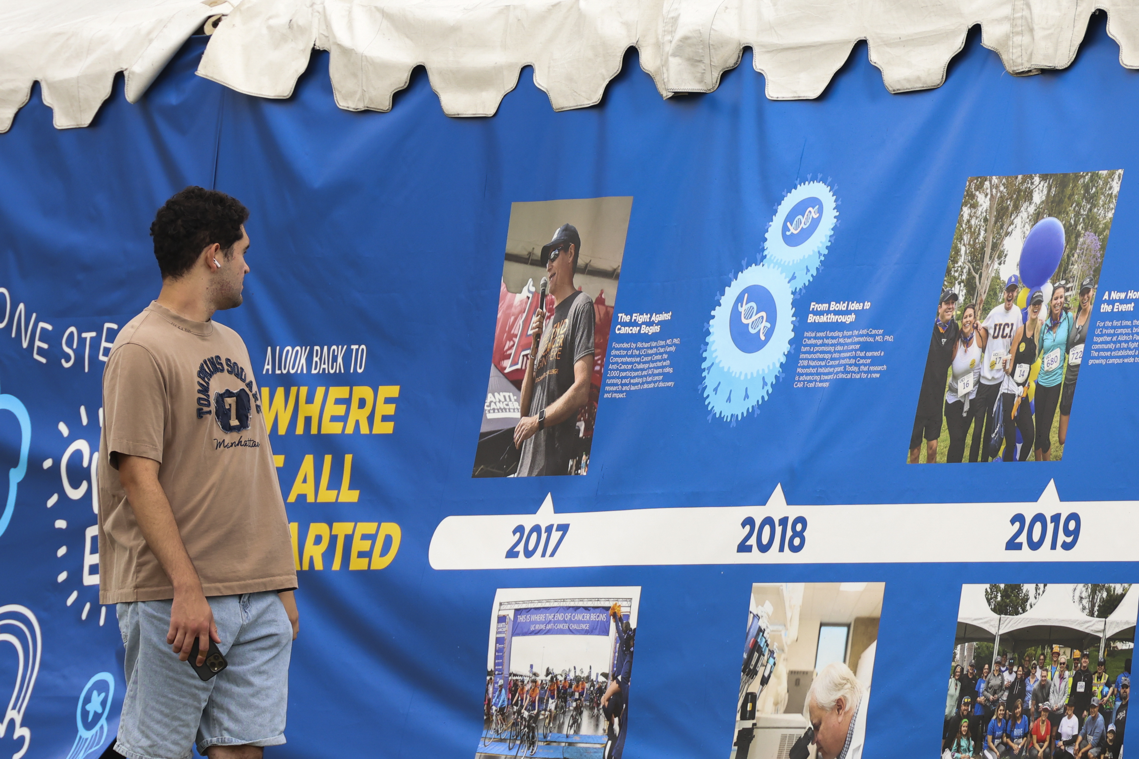 a man walks by a display with a timeline during the 2026 uc irvine anti-cancer challenge 
