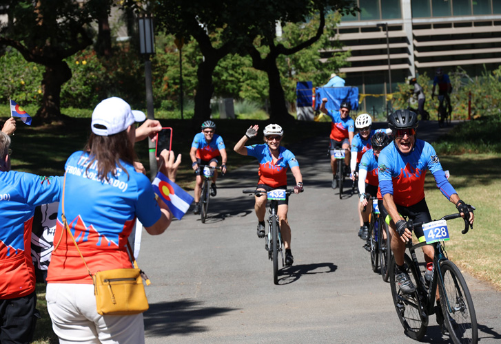 cyclists in the 2025 uc irvine anti-cancer challenge celebrate as they arrive at the finish line