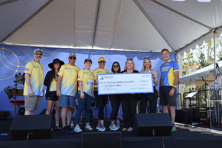 participants in the 2025 uc irvine anti-cancer challenge present a check with the funds they have raised to support cancer research