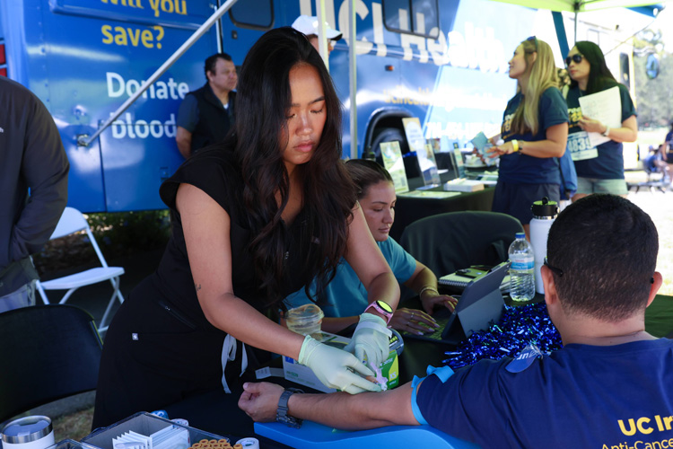 participants in the 2025 uc irvine anti-cancer challenge donate blood and get prepared by a phlebotomist