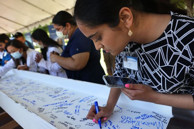 uci health co-worker signs a white beam covered in signatures before the beam tops off uci health irvine