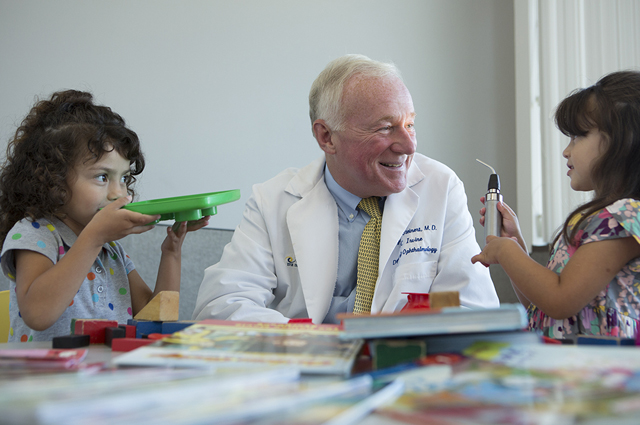 UC Irvine eye surgeon Dr. Roger Steinert gets acquainted with Cassandra, left, and Carley Boyles, far right, in the new children's wing of the Gavin Herbert Eye Institute.