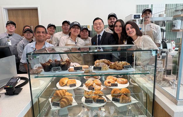 co-workers and uci health leadership pose for a photo behind a pastry display case at the opening of the tony and daisy fan family cafe at the uci health chao family cancer center and ambulatory care building in Irvine