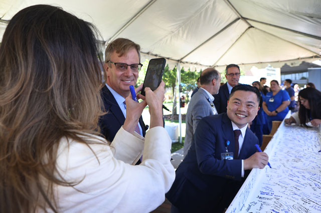 uci health chief operations officer nate shinagawa signs a white beam covered in signatures before the beam tops off uci health irvine