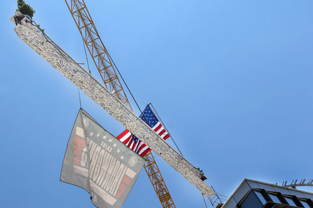 uci health - irvine construction topping off ceremony; beam signed by uci health coworkers is lifted into place on top of the new hospital building, with an american flag on one side and potted plant on the other