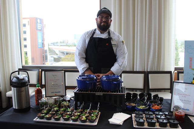 a server stands and smiles with his food at a menu tasting for UCI Health -- Irvine and UCI Medical Center in Orange