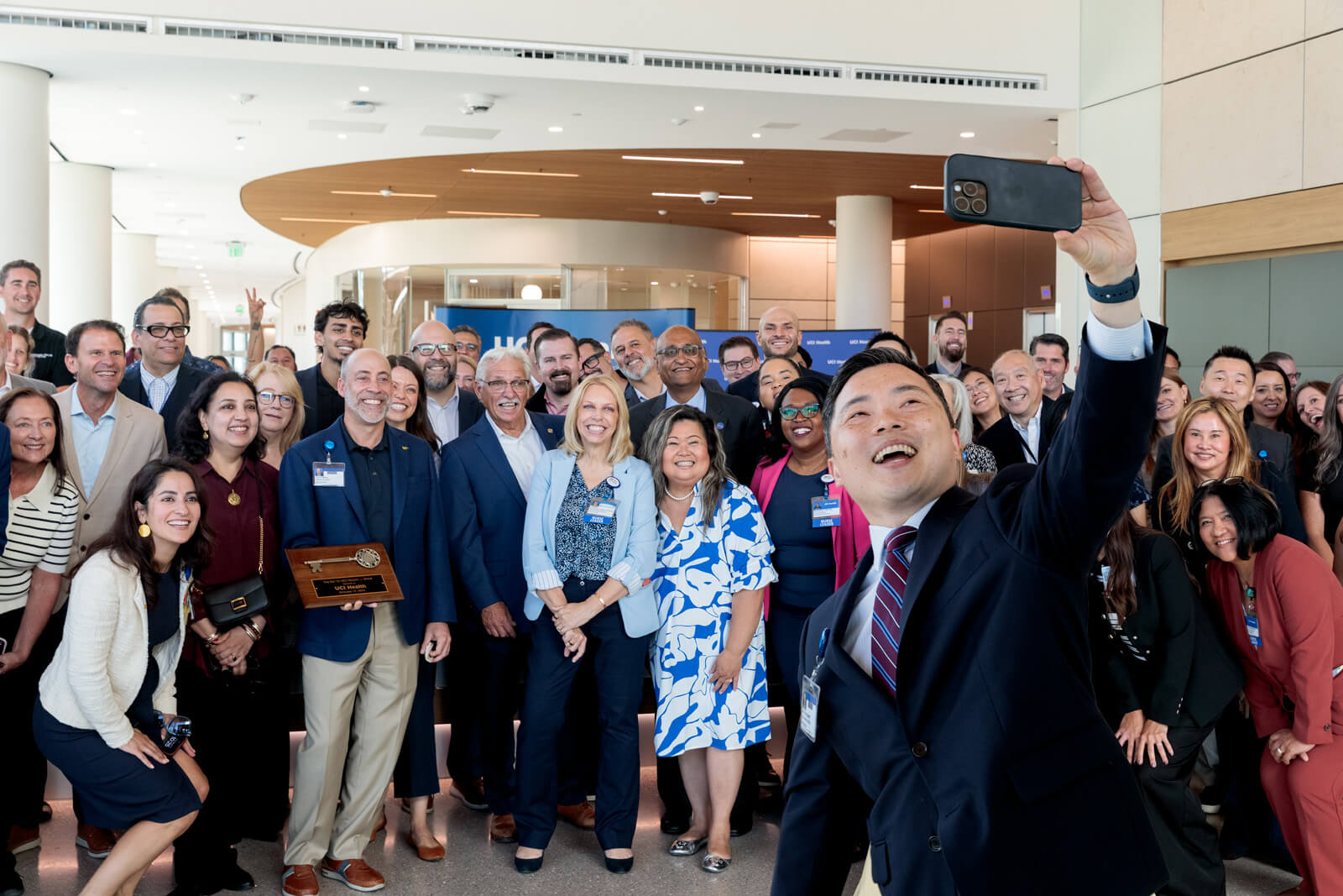 uci health chief operating officer and senior vice president nathan shinagawa shoots a group selfie at the uci health irvine substantial completion event on sept 19 2025