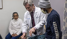 UCI Health transplant surgeon Dr. Donald Dafoe and examines his patient, who received a kidney from his mother, who is looking on.