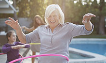Older woman hula hooping in backyard