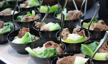 spoons in black bowls full of bok choy and beef pho