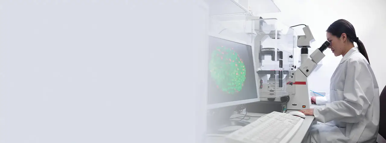 researcher looking through microscope