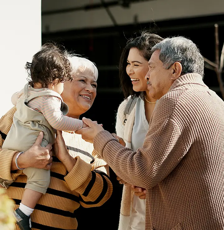 Family of three adults and a toddler enjoy a joyful moment outdoors.