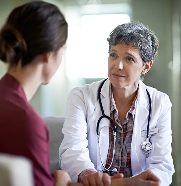 Doctor listens attentively to a patient in a brightly lit medical room.