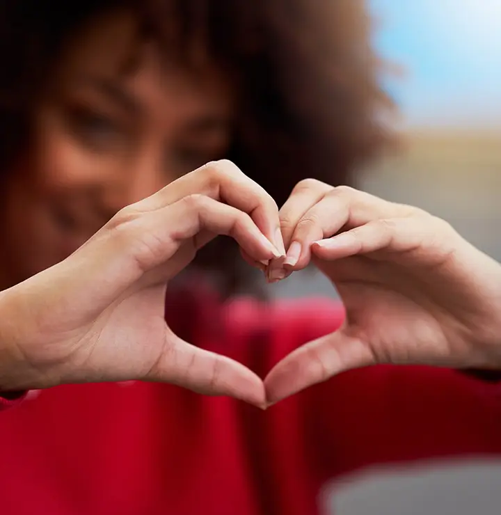 a women in a red sweater holding out her hands in a heart shape