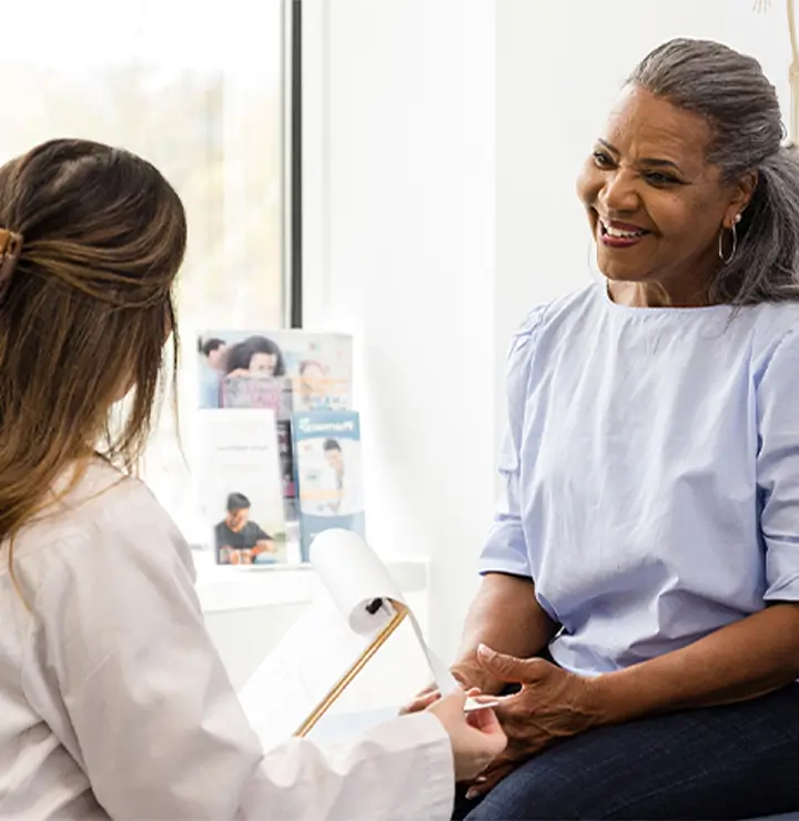 Doctor and older woman with a clipboard share a discussion in a bright office.