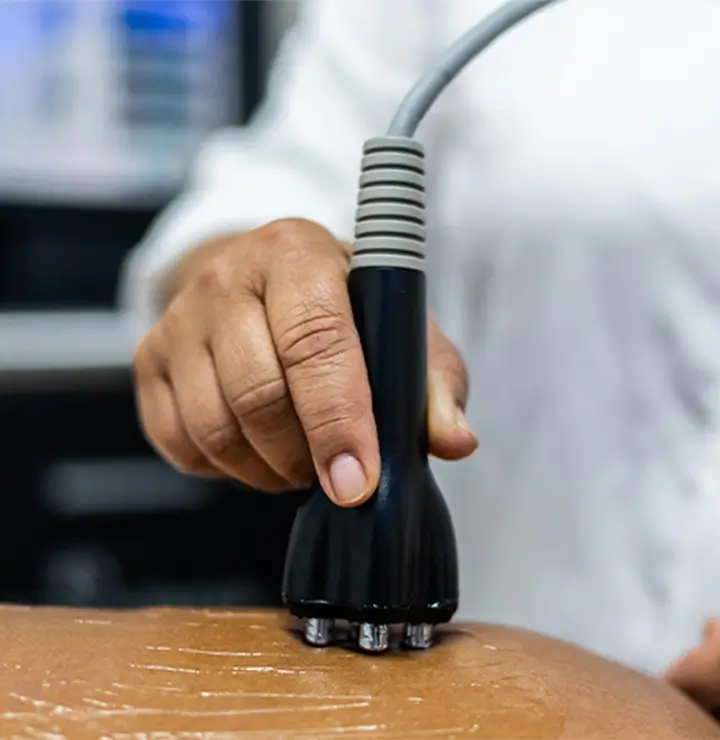 Person uses a medical device with metal prongs on someone’s skin.