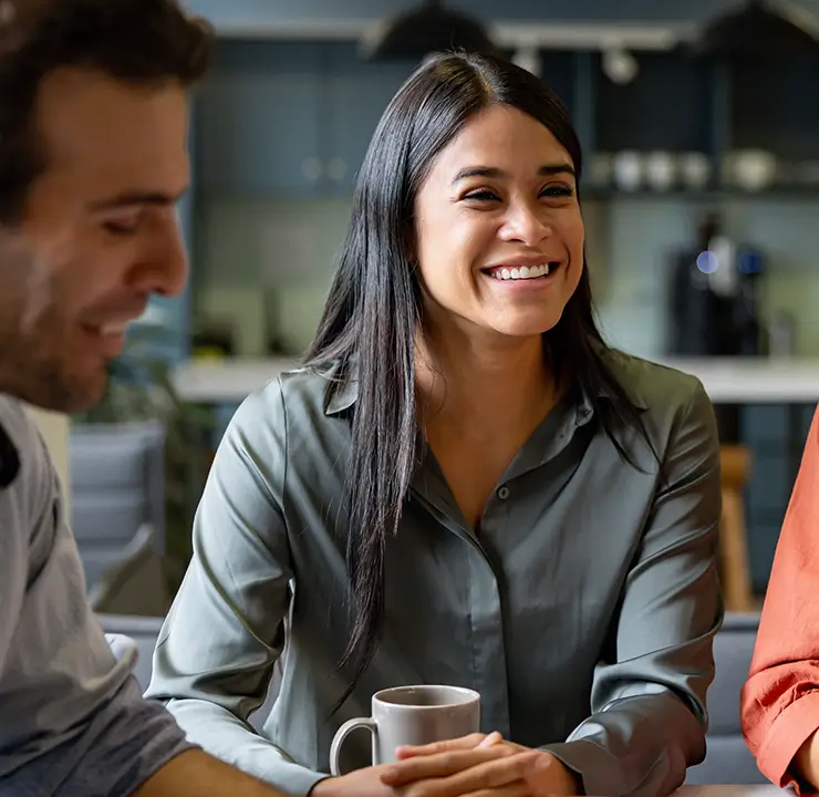 A group of people sitting and smiling in a cozy room with a blurred background.