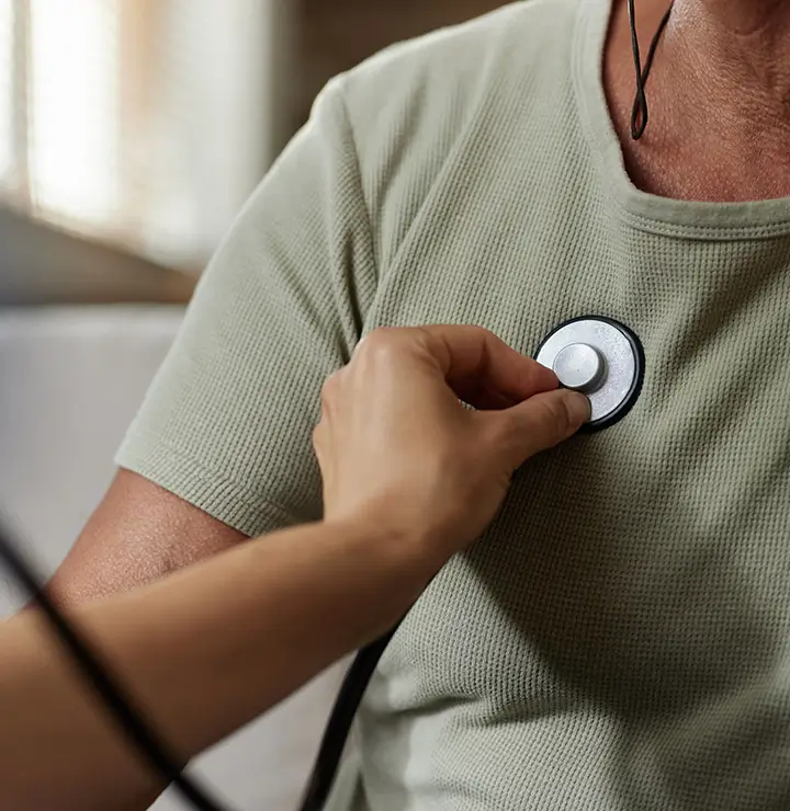 A doctor listens to a patient's heartbeat using a stethoscope placed on the patient's chest.