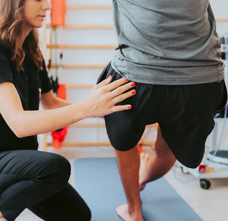 A therapist assists a person with a back exercise in a rehabilitation setting.