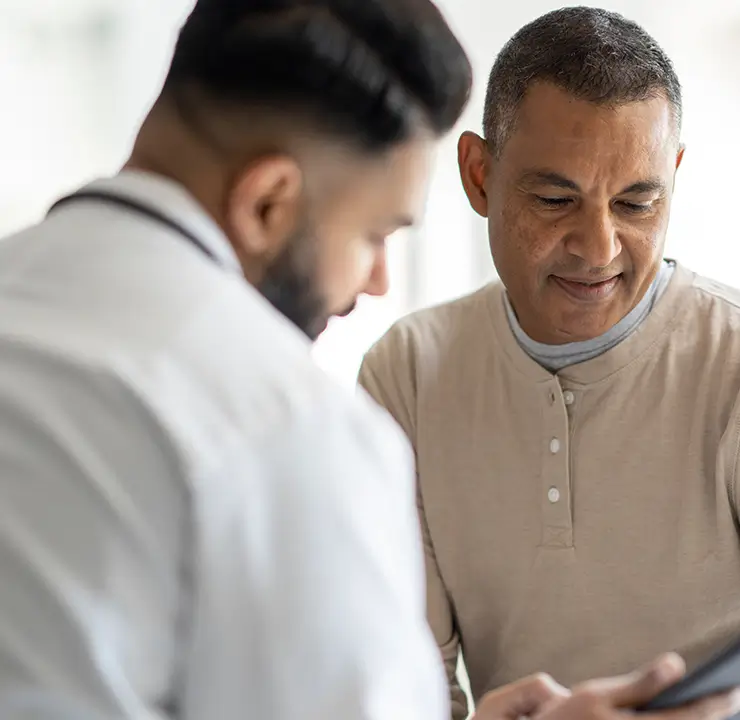 A doctor consults with a male patient in a bright room, reviewing information together.