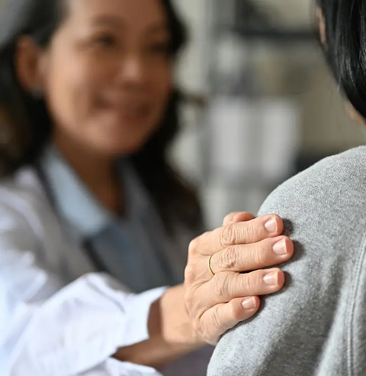 A healthcare professional gently places a hand on a patient's shoulder, providing comfort and support during a consultation.