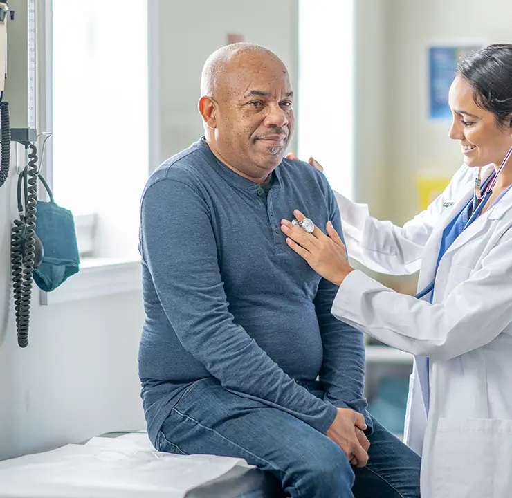 Doctor listens to patient's heartbeat with a stethoscope in a medical office.``