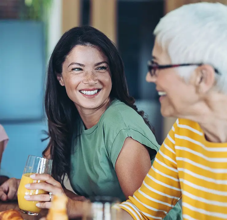 A family of four, including a child and two adults, joyfully eating and laughing together at a table.