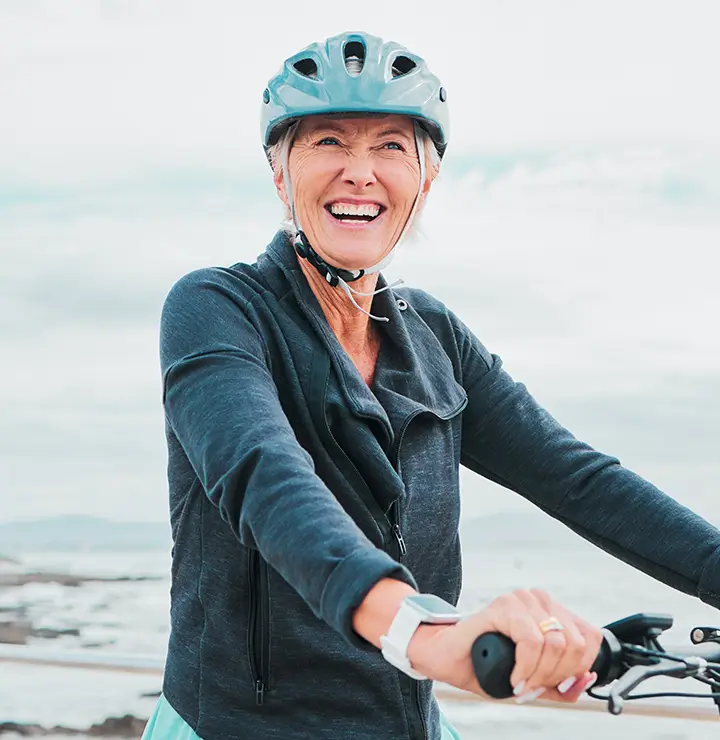 elderly women excitedly rides her bike along the coast