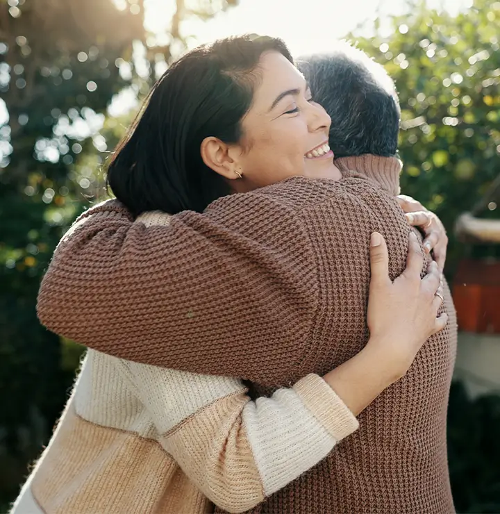 two individuals hug in a deep embrace in the sunlight