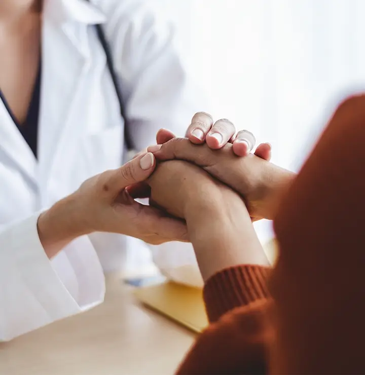 a doctor and patient share a compassionate hand hold
